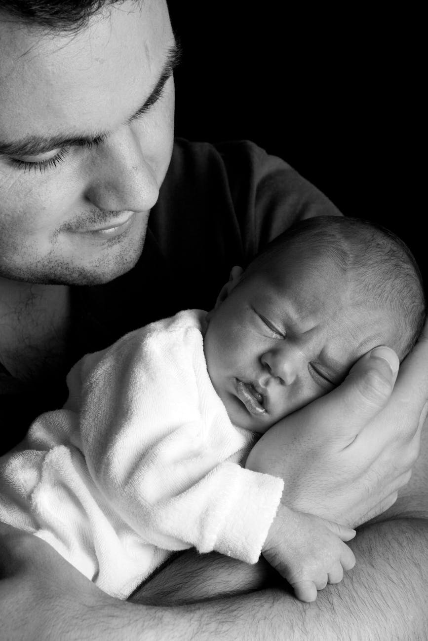 grayscale photo of a man holding a baby