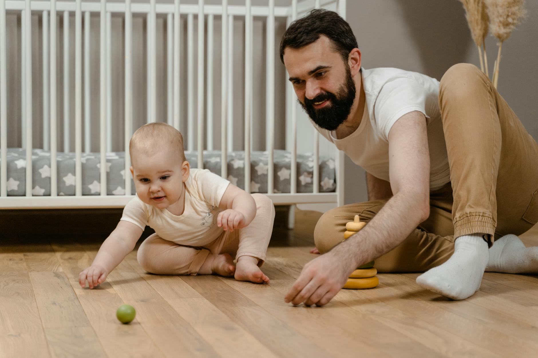 man sitting on wooden floor with his baby
